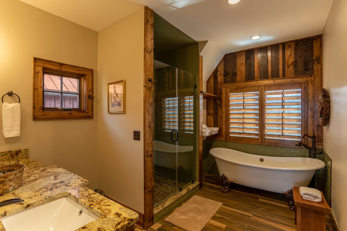 A serene ensuite bathroom with a freestanding bathtub, a glass shower enclosure, and a granite countertop. The space feels spa-like and tranquil, perfect for unwinding after a day in the mountains.